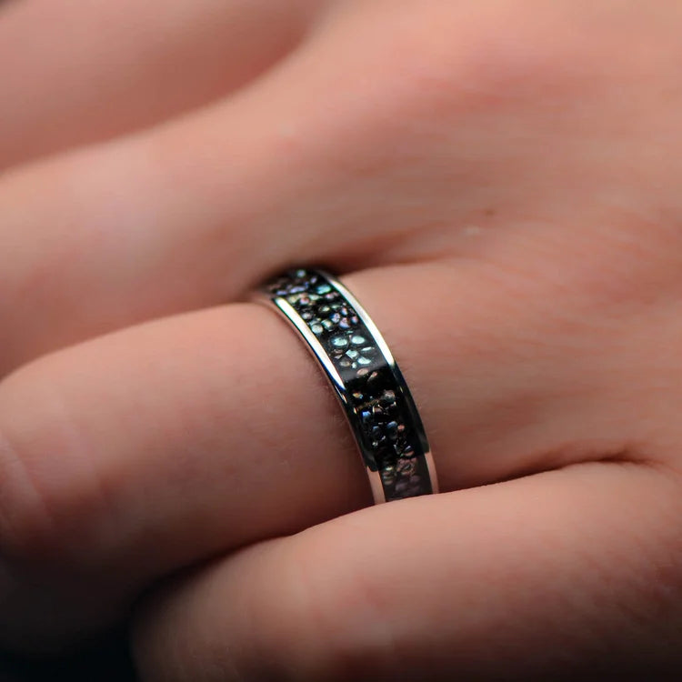 Titanium wedding band with central black pearl inlay, polished flat profile, mens 6mm ring, free engraving, displayed on a white sea branch.
