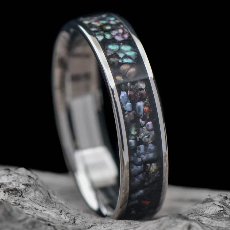 Titanium wedding band with central black pearl inlay, polished flat profile, mens 6mm ring, free engraving, displayed on a white sea branch.