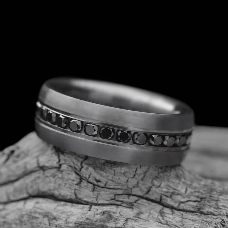 Tantalum wedding band with eternity set precious stones, featuring a brushed domed profile, 7mm mens ring, displayed on a white sea branch, free engraving available.