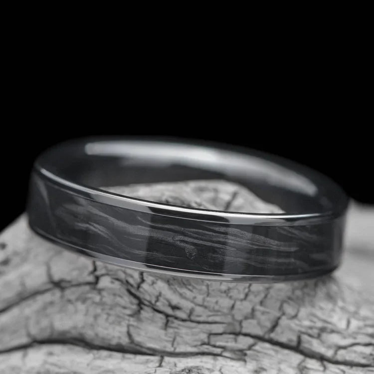Black titanium wedding band with central forged inlay, 5mm, polished flat profile, simple custom ring, free engraving, displayed on a white sea branch.