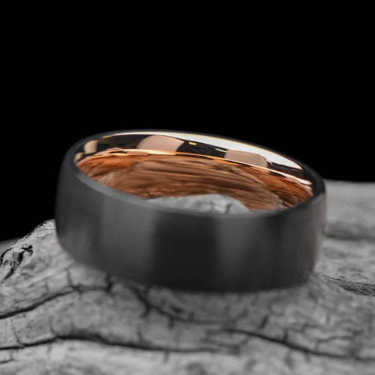 Black titanium wedding band with 18K rose gold inner sleeve, 7mm mens ring, brushed domed profile, on white sea branch, free engraving available.