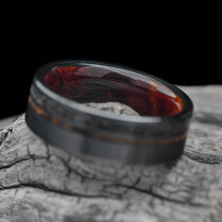 Black titanium wedding band with meteorite and crushed T-Rex inlays, 7mm mens matte flat profile ring, unique mens wedding ring on white sea branch, free engraving available.