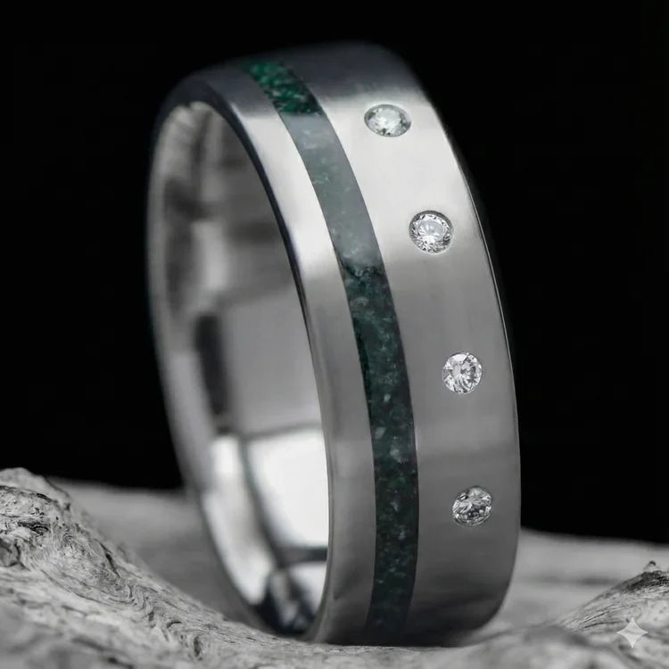 Titanium wedding band with moss agate inlay and flush set diamond, 7mm mens ring with brushed flat profile, free engraving, displayed on white sea branch.
