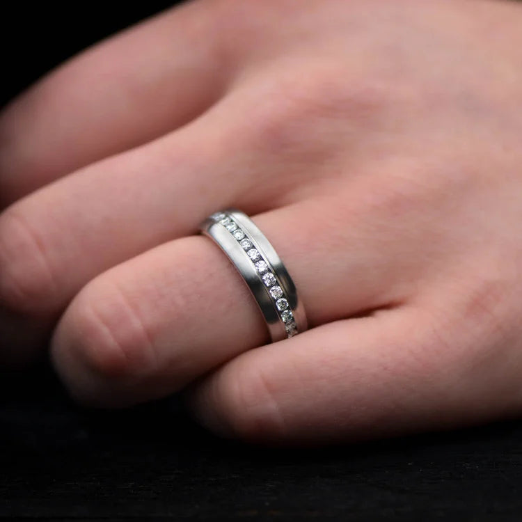 Mens brushed titanium wedding band with whiskey barrel oak inner sleeve and eternity set stones, 7mm, shown on a hand, free engraving available.