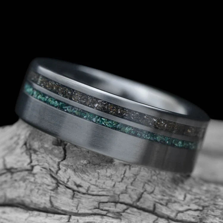 Black titanium wedding band with meteorite and moss agate inlays, 7mm mens ring, unique design, free engraving, displayed on a white sea branch.