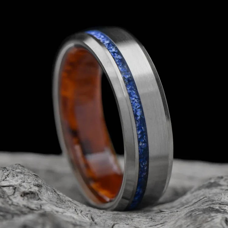 Titanium wedding band with lapis lazuli and amboyna wood inlays, featuring a brushed bevel profile, displayed on a white sea branch. Mens 6mm wedding ring with free engraving option.