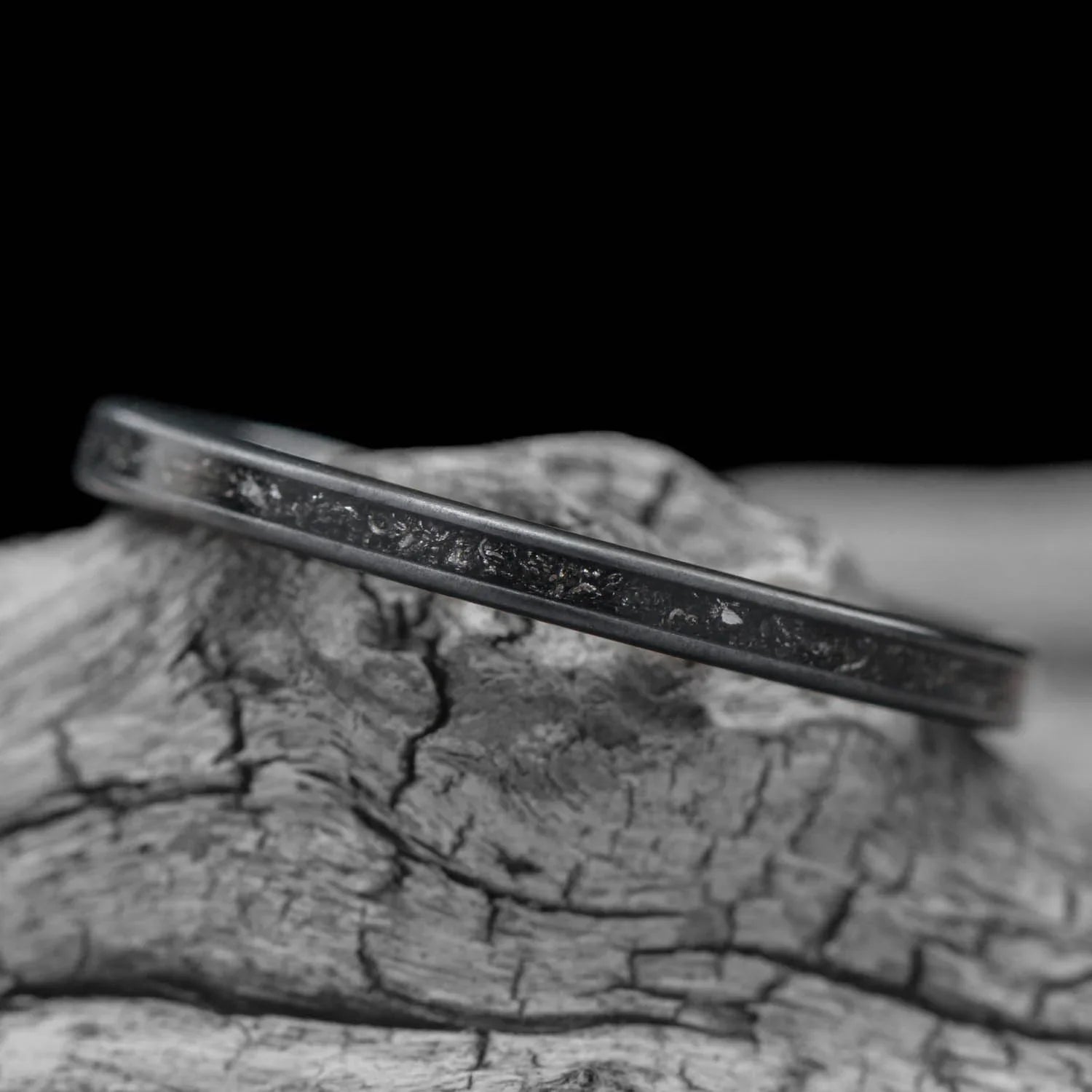 Zirconium wedding band with central meteorite inlay, 2mm womens unique custom ring, free engraving, displayed on white sea branch.