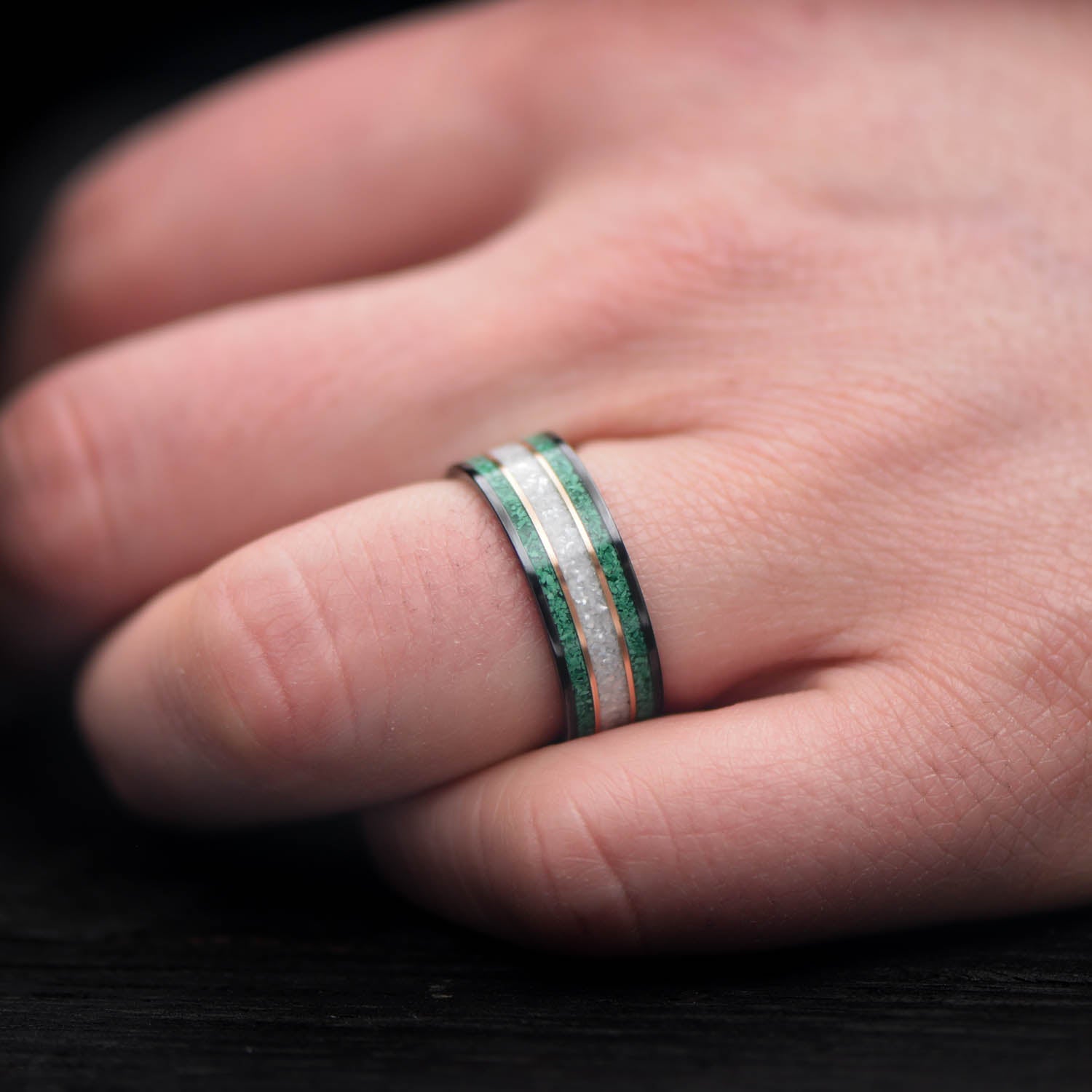 Black titanium wedding band with dual 14K yellow gold inlays and pearl center, 8mm mens ring, custom design, free engraving, displayed on white sea branch.