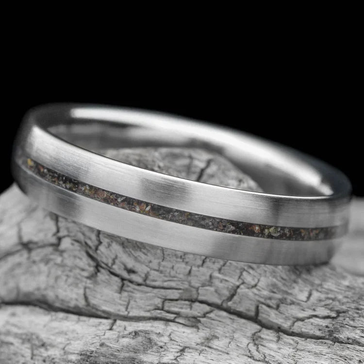 Titanium wedding band with central crushed T-Rex inlay, 5mm, unique custom ring, free engraving, displayed on a white sea branch, simple and elegant design, perfect for weddings and special occasions.