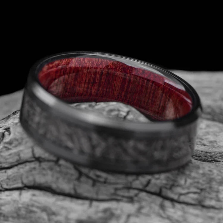 Black titanium mens wedding band with central meteorite inlay and bloodwood inner sleeve, 8mm width, displayed on a white sea branch, offering free engraving for a unique touch.