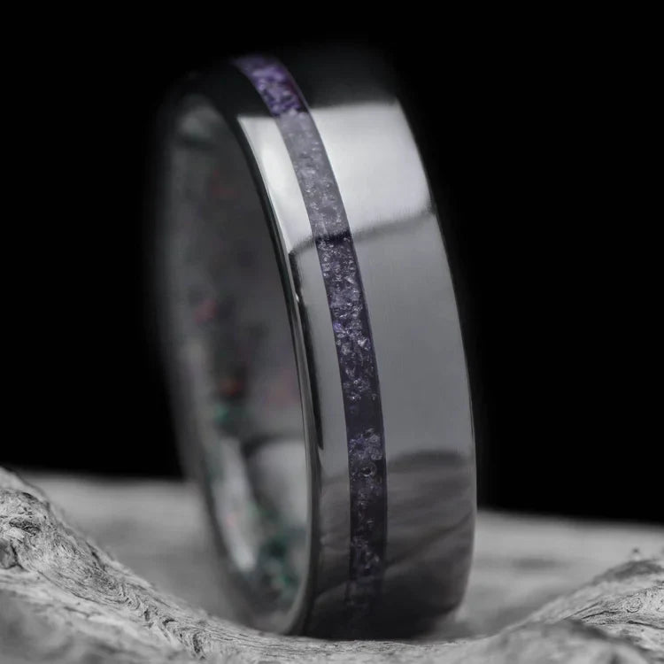 Black titanium wedding band with amethyst and black fire opal inlay, featuring free engraving, 6mm width, mens polished flat profile ring, displayed on a white sea branch.