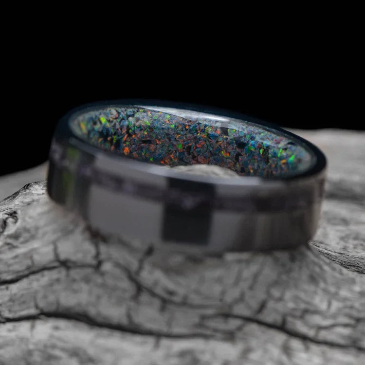 Black titanium wedding band with amethyst and black fire opal inlay, 6mm mens ring, polished flat profile, displayed on a white sea branch, free engraving available.