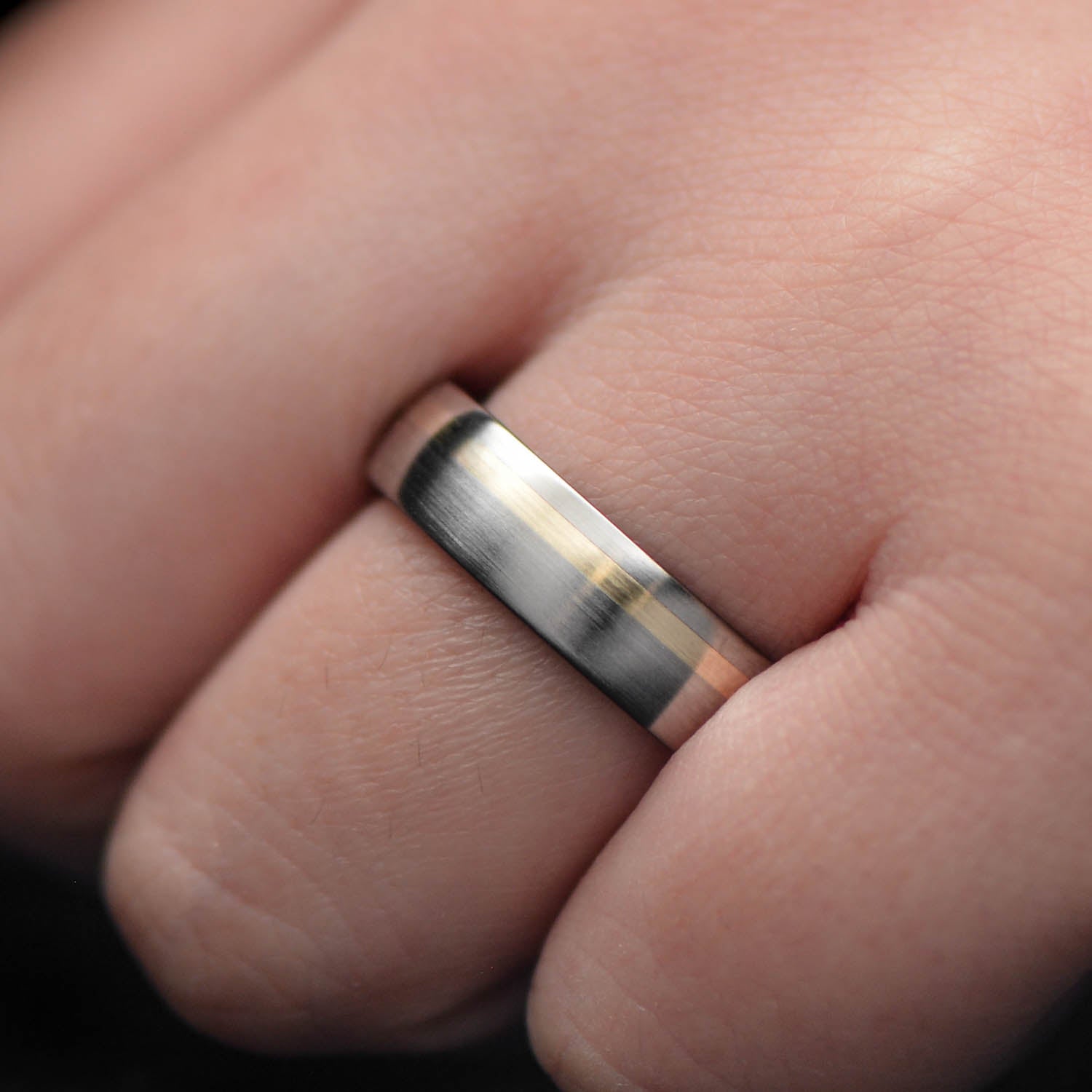 Titanium wedding band with 10KY gold and olivewood inlay, featuring a unique brushed domed profile, displayed on a white sea branch, 6mm mens ring with free engraving.