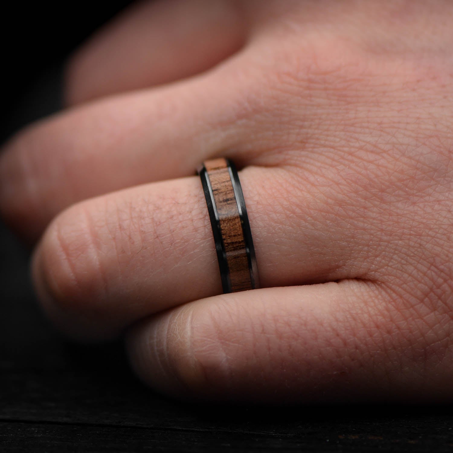 Black titanium wedding band with central walnut inlay, free engraving, 6mm mens wedding ring, brushed bevel profile, on a white background.