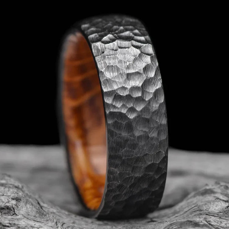 Black Titanium Wedding Band with Whiskey Barrel Oak Inner Sleeve, 7mm Mens Hammered Domed Ring, on white sand beach, unique mens wedding band, free engraving available.