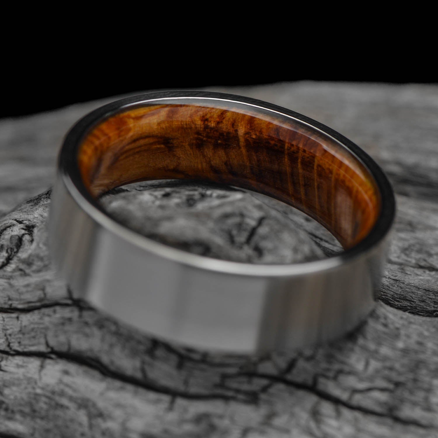 Mens 7mm titanium wedding band with whiskey barrel oak inner sleeve, featuring a brushed flat profile, available with free engraving, displayed on a white background.
