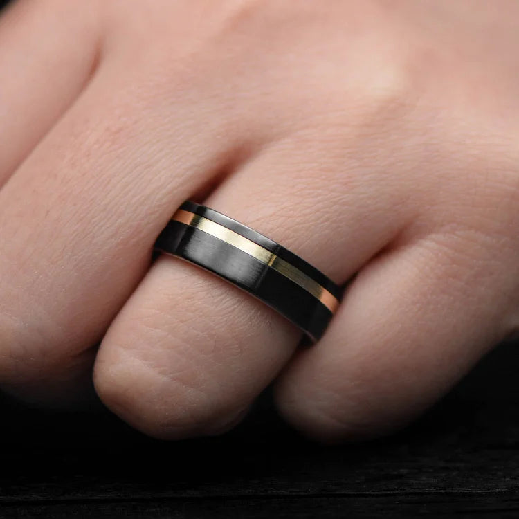 Black titanium wedding band with 10KY gold and whiskey barrel oak inlay, 7mm mens ring, unique design, free engraving, displayed on white sea branch.