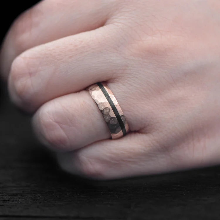 14K rose gold mens wedding band with unidirectional inlay, 7mm faceted domed profile, custom ring with free engraving, shown on a hand.