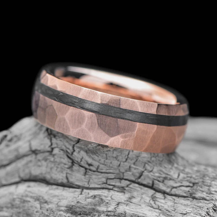 14K rose gold mens wedding band with unidirectional inlay, 7mm faceted domed profile, custom ring with free engraving, shown on a hand.