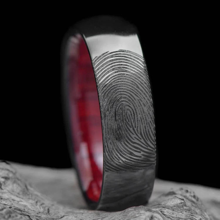 Black titanium wedding band with bloodwood inner sleeve, 7mm mens domed polished ring, unique design, free engraving, displayed on white sea branch.