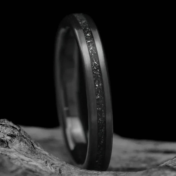 Black Titanium wedding band with central meteorite inlay, 3mm womens ring, unique custom design, free engraving, displayed on white sea branch.
