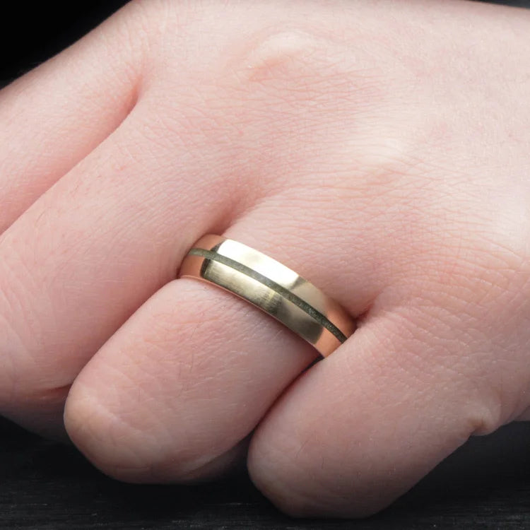 14K yellow gold mens wedding band with custom inlay and central emerald, 6mm brushed domed design, shown on a hand, featuring free engraving option.