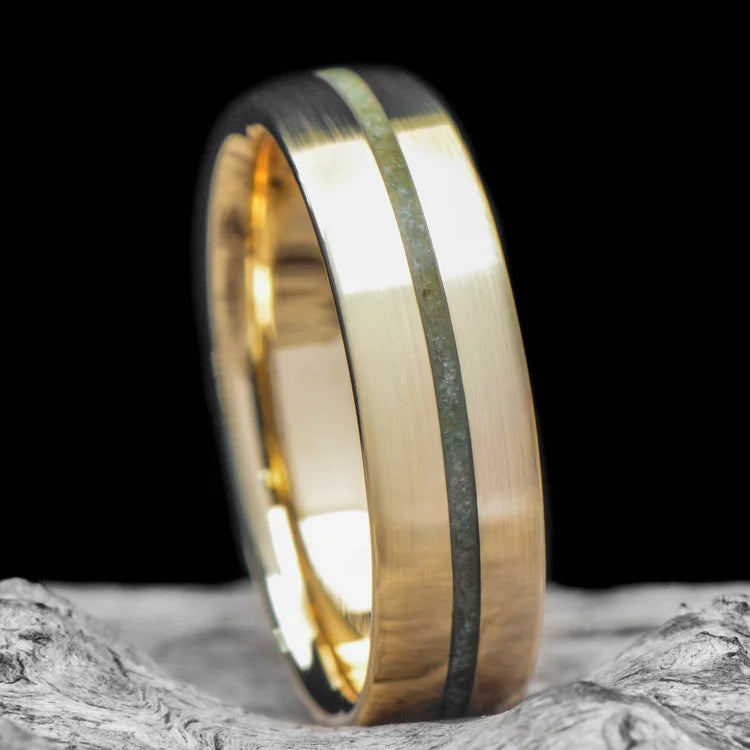 14K yellow gold wedding band with custom inlay featuring a central emerald, 6mm brushed domed mens ring, displayed on a white sea branch. Free engraving available. Perfect for weddings and special occasions.
