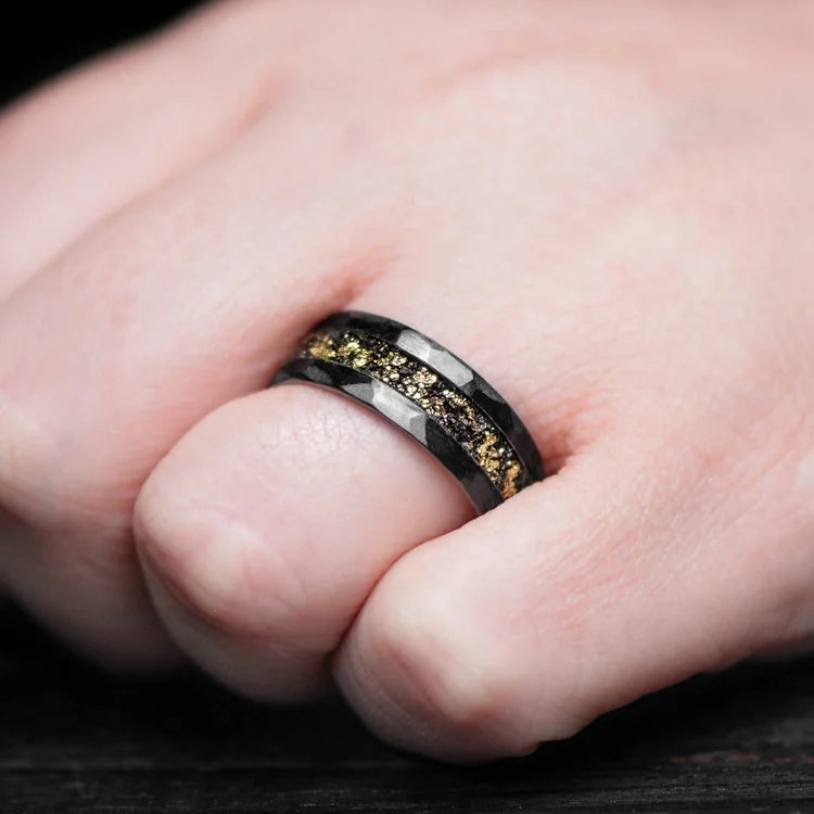 Mens wedding band on hand, featuring an 8mm black titanium ring with central meteorite and gold leaf inlay, unique design, free engraving option available.