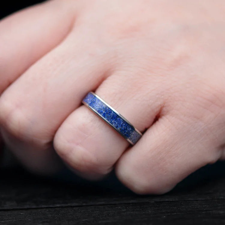 Titanium wedding band with central lapis lazuli inlay on a hand, featuring free engraving, 5mm custom simple ring, unique wedding band design.