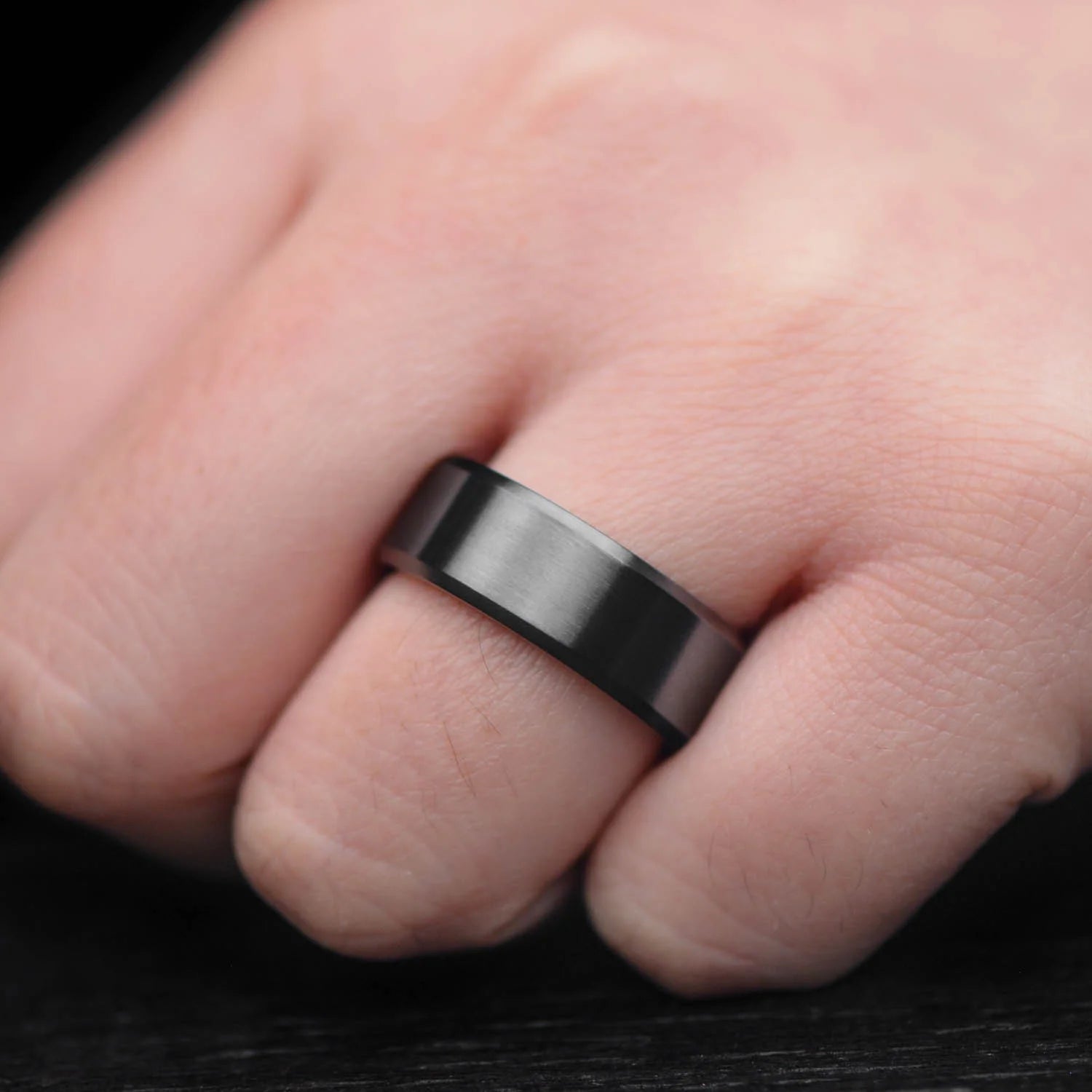Black Titanium Wedding Band with T-Rex Inner Sleeve on a hand, showcasing its unique design and 8mm width, perfect for mens wedding rings with free engraving options.