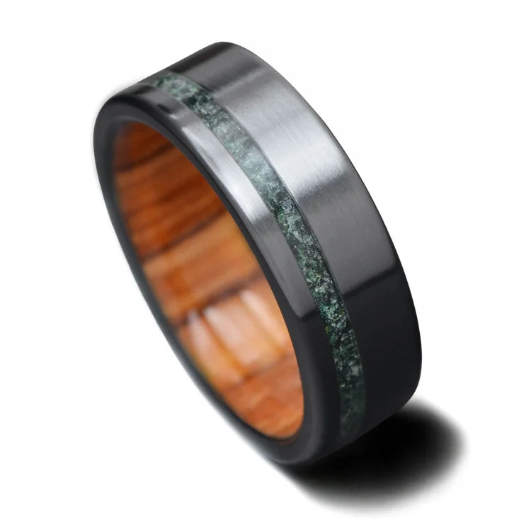 Black titanium wedding band featuring a moss agate and olivewood inlay, 7mm mens ring, unique design, free engraving available, displayed on a white background.