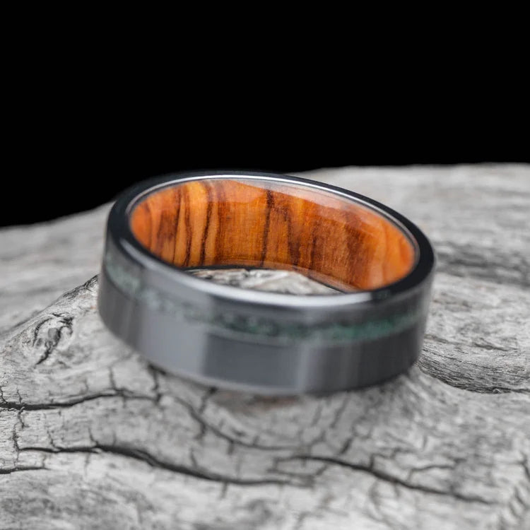 Black titanium wedding band with moss agate and olivewood inlay, 7mm mens ring, unique design, free engraving, displayed on a white sea branch.