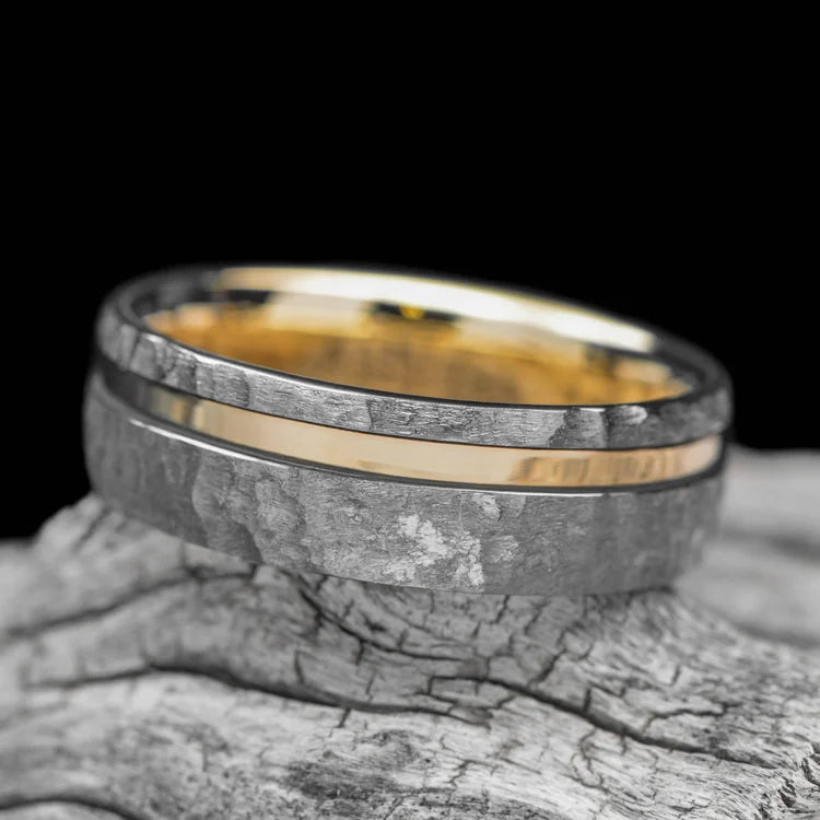 Faceted tantalum wedding band with 14K yellow gold inlay and inner sleeve, 8mm mens ring, unique design, laying on white sea branch, free engraving available.