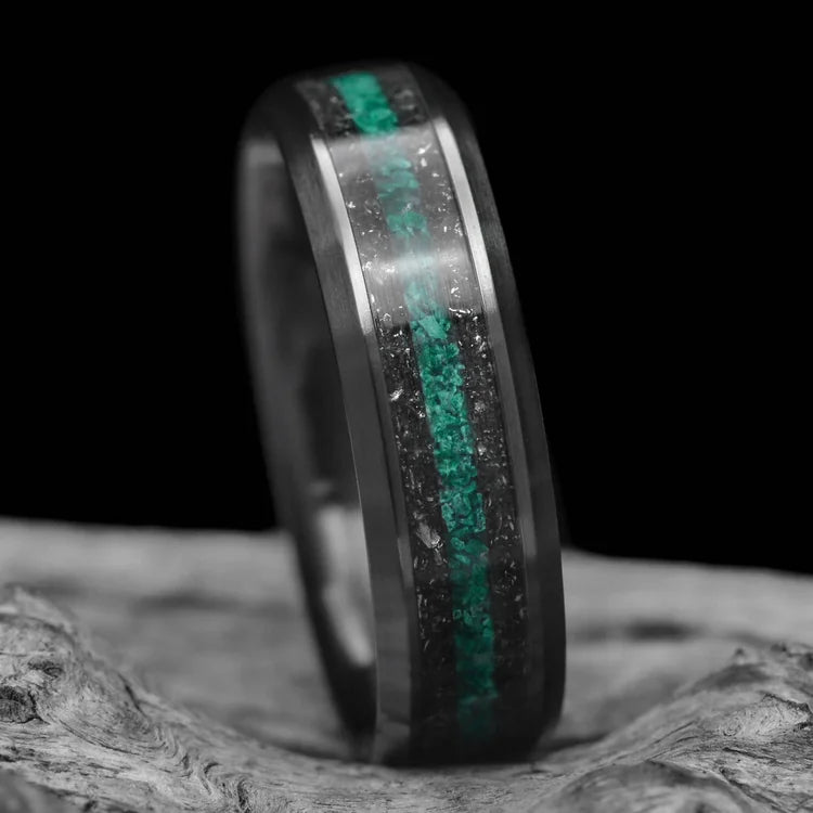 Black titanium wedding band with dual meteorite and central malachite inlays, 6mm mens ring, displayed on a white sea branch, unique mens wedding ring with free engraving.