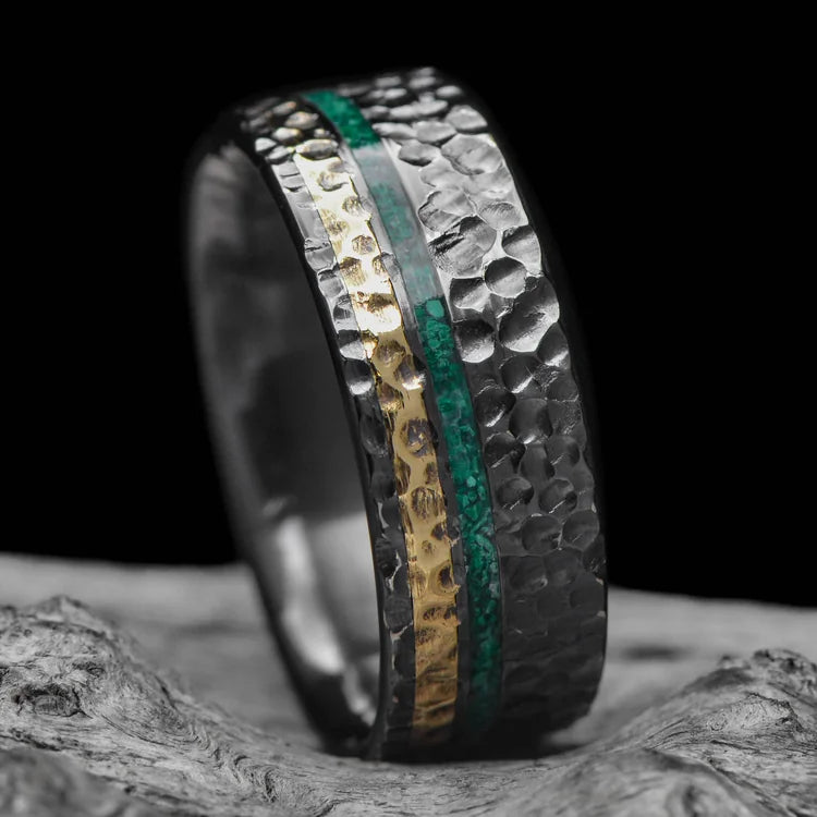 Black titanium wedding band with 18K yellow gold and malachite inlays, 8mm mens ring, hammered flat profile, unique design, free engraving, displayed on white sea branch.