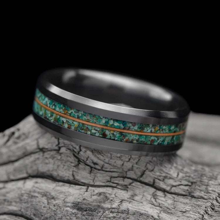 Black titanium wedding band with dual turquoise and central guitar string inlay, 7mm mens ring, unique design, free engraving, displayed on a white sea branch.