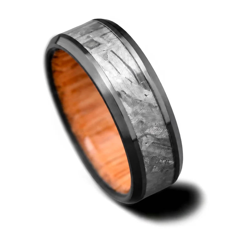 Black titanium wedding band featuring a solid meteorite central inlay and oak inner sleeve, 7mm mens ring with brushed beveled edges, available with free engraving, displayed on a white background.