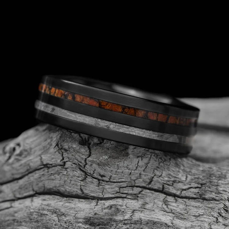 Black titanium wedding band with solid meteorite and T-Rex inlays, 7mm mens ring, unique design, free engraving, displayed on white sea branch.