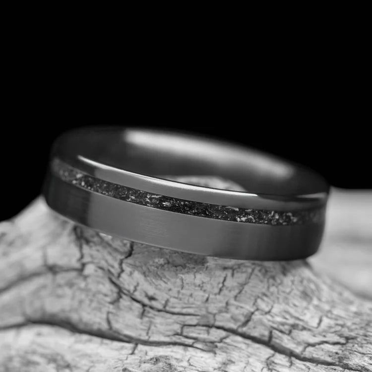 Black titanium wedding band with meteorite inlay, 5mm custom flat brushed design, unique simple wedding band, free engraving, displayed on a white sea branch.