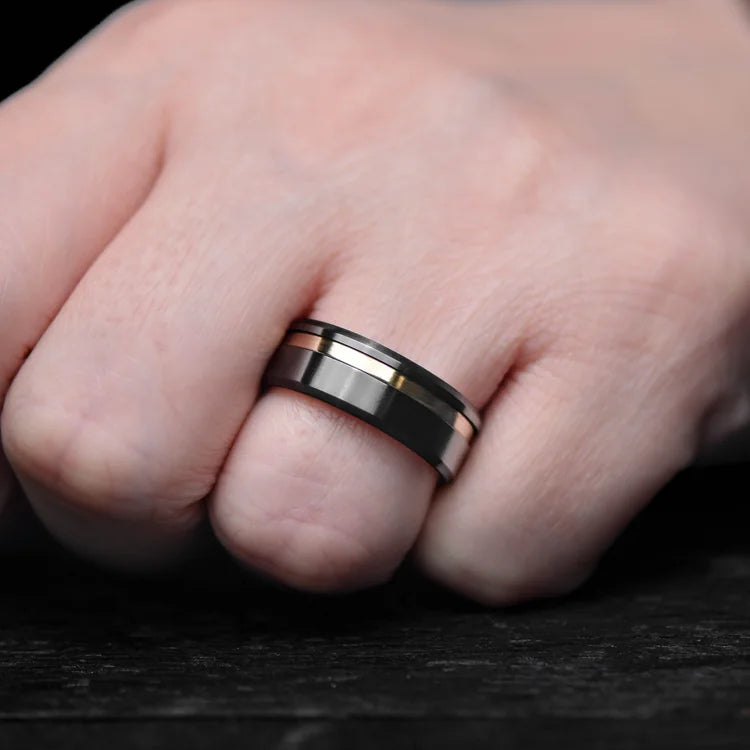 Mens black titanium wedding band with 14K yellow gold inlay and brushed bevel profile, 8mm width, custom ring with free engraving, shown on a hand.
