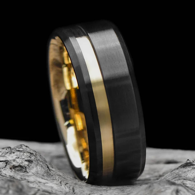 Black titanium wedding band with 14K yellow gold inlay and brushed bevel profile, 8mm mens ring, resting on a white sea branch, custom design, free engraving available.