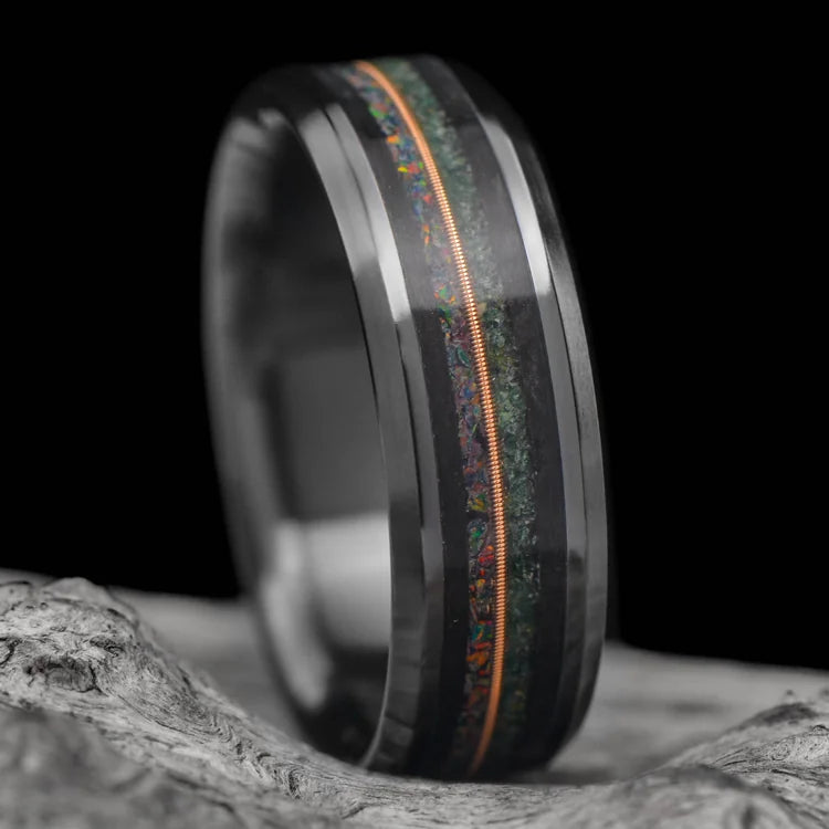 Black Titanium Wedding Band with Moss Agate and Black Fire Opal Inlays, featuring a central forged guitar detail, displayed on a white sea branch, 7mm mens wedding ring with free engraving.