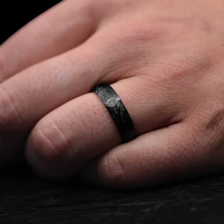 Mens black titanium wedding band with 14K yellow gold inner sleeve, faceted domed profile, 6mm width, unique design, free engraving, worn on a hand.