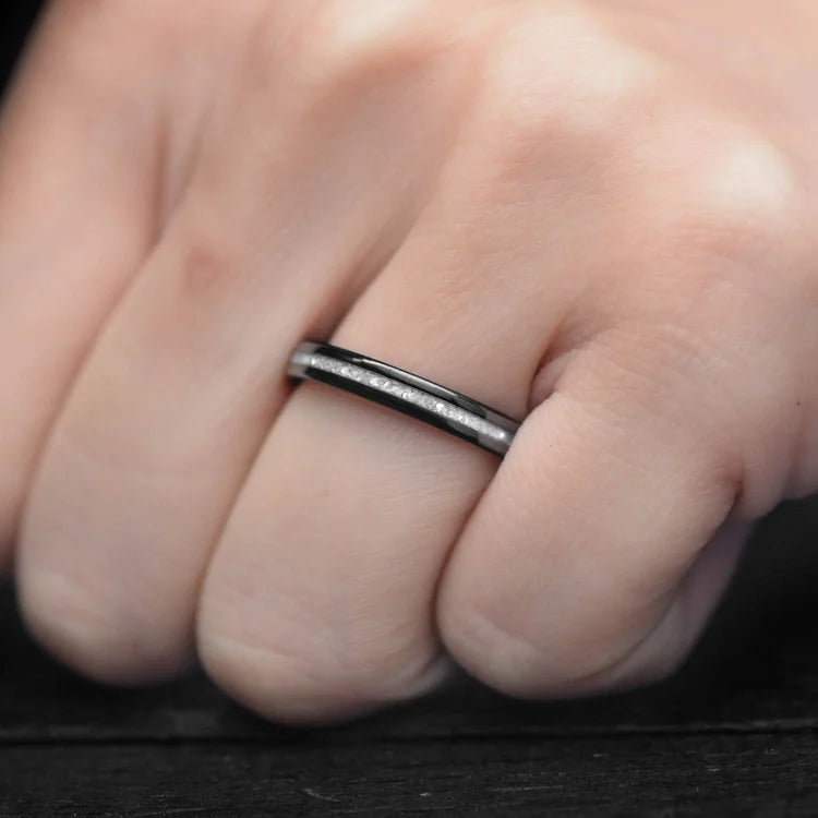 Black titanium wedding band with central pearl inlay on a womans hand, featuring a polished flat profile and custom bridal design, 3mm width, free engraving available.
