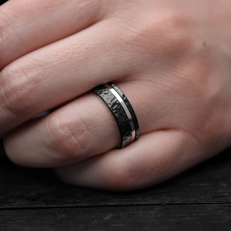 Mens black titanium wedding band with 14K white gold inlay and faceted finish, 7mm, unique design, free engraving, worn on a hand.