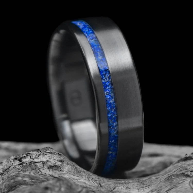 Black titanium ring with lapis lazuli inlay, 8mm mens wedding band, brushed flat profile, unique design, free engraving, displayed on white sea branch.