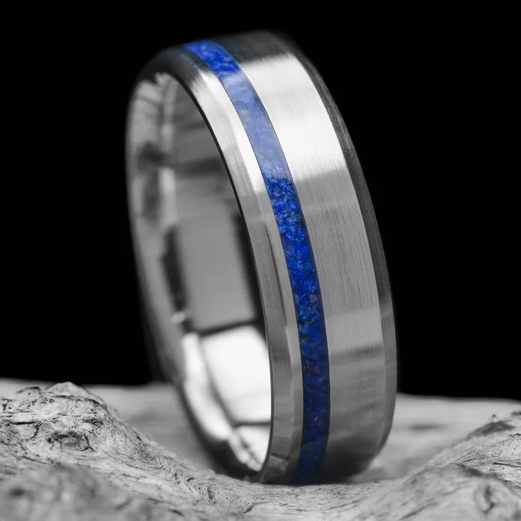 Titanium wedding band with lapis lazuli inlay, 7mm mens ring with brushed bevel profile, unique design, free engraving, displayed on white sand beach.