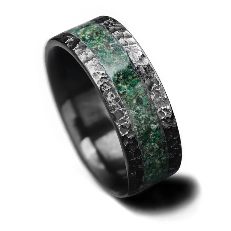 Black titanium mens wedding band with central moss agate inlay, featuring a unique hammered flat profile, 8mm wide, available with free engraving, displayed on a white background.