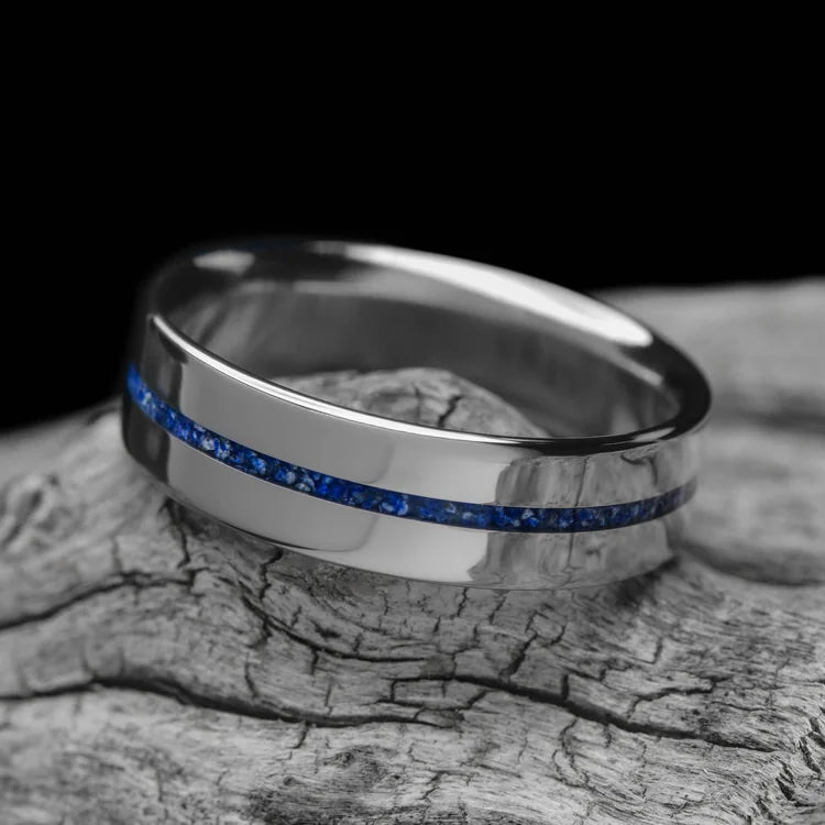 Titanium wedding band with central lapis lazuli inlay, 6mm mens ring, polished flat profile, unique design, free engraving, displayed on white sea branch.