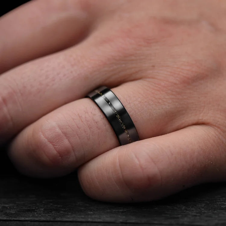 Mens 7mm zirconium wedding ring with central crushed T-Rex inlay, brushed flat profile, worn on a hand, unique mens wedding band with free engraving.